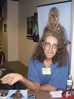 O actor britanico Peter Mayhew, en una imachen de 2008, con un poster dezaga a on se veye o suyo personache de Chewbacca.