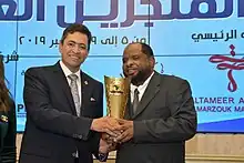 محمد توفيق بلو يتسلم جائزة أوسكار الإبداع العربي لعام 2019م من اللواء د. سامح لطفي رئيس الاتحاد الدولي للمنجزين العرب والأفارقة 05 ديسمبر 2019م