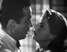 A black-and-white screenshot of a man and woman close together appearing ready to kiss.