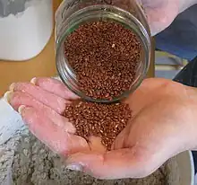 Flaxseed is poured from a jar into the hand.