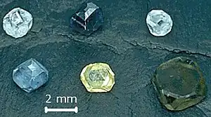 Six non-faceted diamond crystals of 2–3 mm size; the diamond colors are yellow, green-yellow, green-blue, light-blue, light-blue and dark blue