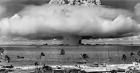 Photograph of a mushroom cloud explosion in a tropical setting