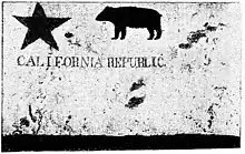 A tattered flag with a five-point star in the upper left, a four-legged animal in the upper middle and "California Republic" written in the middle.