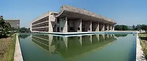 A modernist concrete building, a pond in front