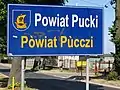 Bilingual sign in Polish and Kashubian in Pogórze, Puck County, Poland, on road from غدينيا to Rewa