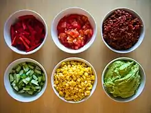 small bowls of corn, tomatoes, peppers, guacamole, and other ingredients