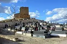 Vista xeneral de les ruines del castiellu-torrexón de Pajarón (Cuenca), con detalle del campusantu municipal en primer planu (2017).