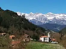 Vista de Cabezón de Liébana. La ilesia parroquial en primer términu. Al fondu, los Picos d'Europa.