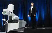 Musk standing next to bulky medical equipment on a stage