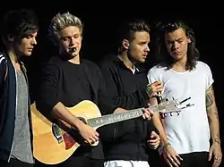 One Direction 2015-ci ildə Qlazqoda On the Road qastrol səfərində çıxış edərkən. Soldan sağa: Lui Tomlinson, Nayl Horan, Liam Peyn və Harri Stayls