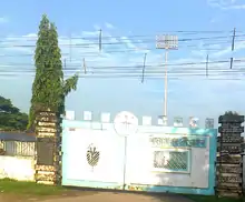 White gate with stone pillars and a tree