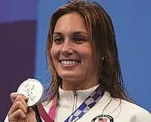 Walsh im weißen Trainingsanzug mit dem Wappen der Vereinigten Staaten. Mit der rechten Hand präsentiert sie ihre Medaille.