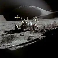 Jim Irwin und das Mondauto von Apollo 15 mit dem Mons Hadley im Hintergrund