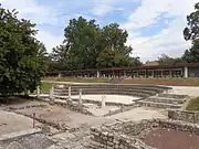 Im Vordergrund einige der konservierten Grundmauern, dahinter das 1995–1998 errichtete Theater und im Hintergrund das Lapidarium