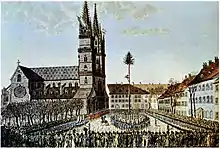 Die Verbrüderungsfeier auf dem Münsterplatz in Basel vom 22. Januar 1798 in einer zeitgenössischen kolorierten Radierung. In der Mitte des Platzes steht der Freiheitsbaum als Zeichen der Rechtsgleichheit. Kolorierte Radierung