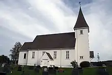 Foto einer weiß gestrichenen Holzkirche mit einem Friedhof im Vordergrund