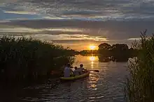 Drei Jungs in einem Kajak bei Sonnenuntergang auf dem Blankenburger See