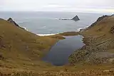 Foto mit Blick von einem Berg über einen See auf das Meer, in dem eine Insel liegt