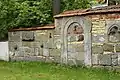 Steinelemente einer alten gotischen Kirche, eingemauert in eine Friedhofsmauer