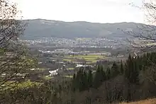 Foto von einer Anhöhe herab auf eine Ortschaft, die an einem Fluss liegt.