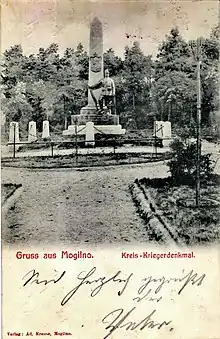 Mogilno: Das Kreis-Kriegerdenkmal 1870/71 (errichtet 1903) mit einem Reliefmedaillon Kaiser Wilhelms I.; vor dem Obelisk steht ein preußischer Jäger mit Gewehr.