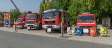 Das Foto zeigt den Fuhrpark einer Freiwilligen Feuerwehr, bestehend aus einem Verkehrssicherungsanhänger und 4 Fahrzeugen