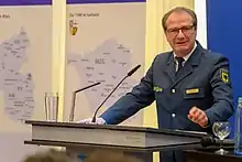 Gerd Friedsam an einem Podium mit Mikrofonen. Im Hintergrund Karten mit den THW-Standorten der Bundesländer