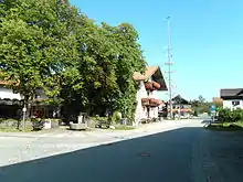 Dorfstraße in Grainbach mit der Traditionsgaststätte Maurer (links im Bild); vor deren Biergarten der Samerbrunnen, flankiert von zwei Sitzbänken