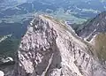 Kaiserkopf von Norden mit Nordgrat, davor die Rote-Rinn-Scharte, hinten rechts der Hirschanger (grasiger Sattel) mit Übergang zum Treffauer, im Tal links Going am Wilden Kaiser, rechts Ellmau