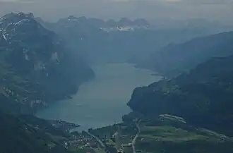 Streusiedlung und Strassenübergang Kerenzerberg über der bewaldeten Felswand am Südufer des Walensees, hier rechts, aus Westen vom Hirzli gesehen