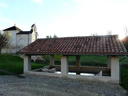 Waschhaus, dahinter die Ortskirche