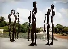 Sechs circa drei Meter hohe Bronzefiguren vor einem rechteckigen Teich am Palais de Lomé, Togo