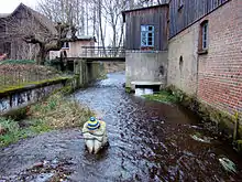 Ehemalige Wassermühle an der Lutter in Marwede, mit Steinskulptur “Die Heide aus Lüneburg” von Petra Förster