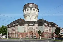 Perrey baute die Luzenbergschule (1913–1915) um den Wasserturm herum.