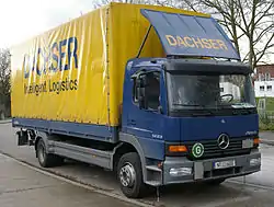 Photo eines parkenden LKW, an dessen Fahrzeugvorderseite das Zeichen „Geräuscharmes Kraftfahrzeug“ angebracht ist.