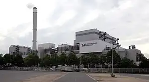 Das Müllheizkraftwerk Darmstadt vor einem bewölkten Himmel, davor eine Reihe Bäume.