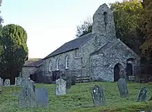 Eine Steinkirche auf einem Friedhof mit Veranda und Glockenstuhl