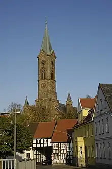 Ortsbild mit Kirchturm und Verlauf der Durchgangsstraße durch ein historisches Fachwerkgebäude