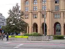 Im Vordergrund eine Straße, dahinter ein Haus, dazwischen eine niedrige Betonmauer mit gelben Leuchtbausteinen