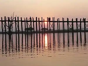 Mönche überqueren bei Sonnenuntergang die U-Bein-Brücke