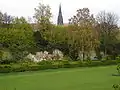 Die Reste des „Neuwerk“. Vor der Hecke fließt die Aa. Im Hintergrund der Turm der Lambertikirche.