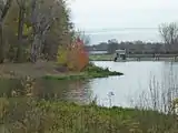 Abzweig der Nahle (links) vom Elsterbecken, im Hintergrund das Luppewehr, die Bahnstrecke und der Wahrener Wasserturm