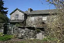 Ein Haus in mittlerer Entfernung, eine Gartenmauer und ein Tor