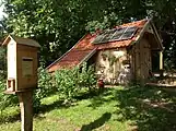 Scheune mit Solaranlage. Im Vordergrund ein Bienenschaukasten