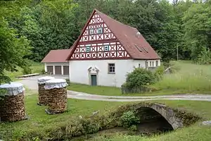 Schmuckseite der Schwarzmühle. Im Vordergrund: Weismain mit Steinbrücke