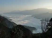 Wolkenmeer in den Tälern des Alishan. Eine geschlossene Wolkendecke verdeckt den Talgrund unter dem strahlend blauen Himmel.