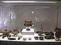 Im Vordergrund links ein aus Goldblech gefertigtes Diadem (daneben ein vom Museum in die Vitrine gestelltes Vergrößerungsglas)