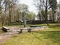 Gedenkplatz auf dem Waldfriedhof, im Hintergrund die Ruine des Krematoriums