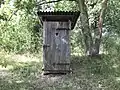 Toilettenhäuschen aus Holz an einem Teich in Brandenburg nahe der Grenze zu Polen