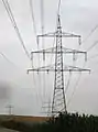 Donaumast mit drei Ebenen und vier Systemen (220/110 kV), dahinter Betonmast einer Mittelspannungsleitung